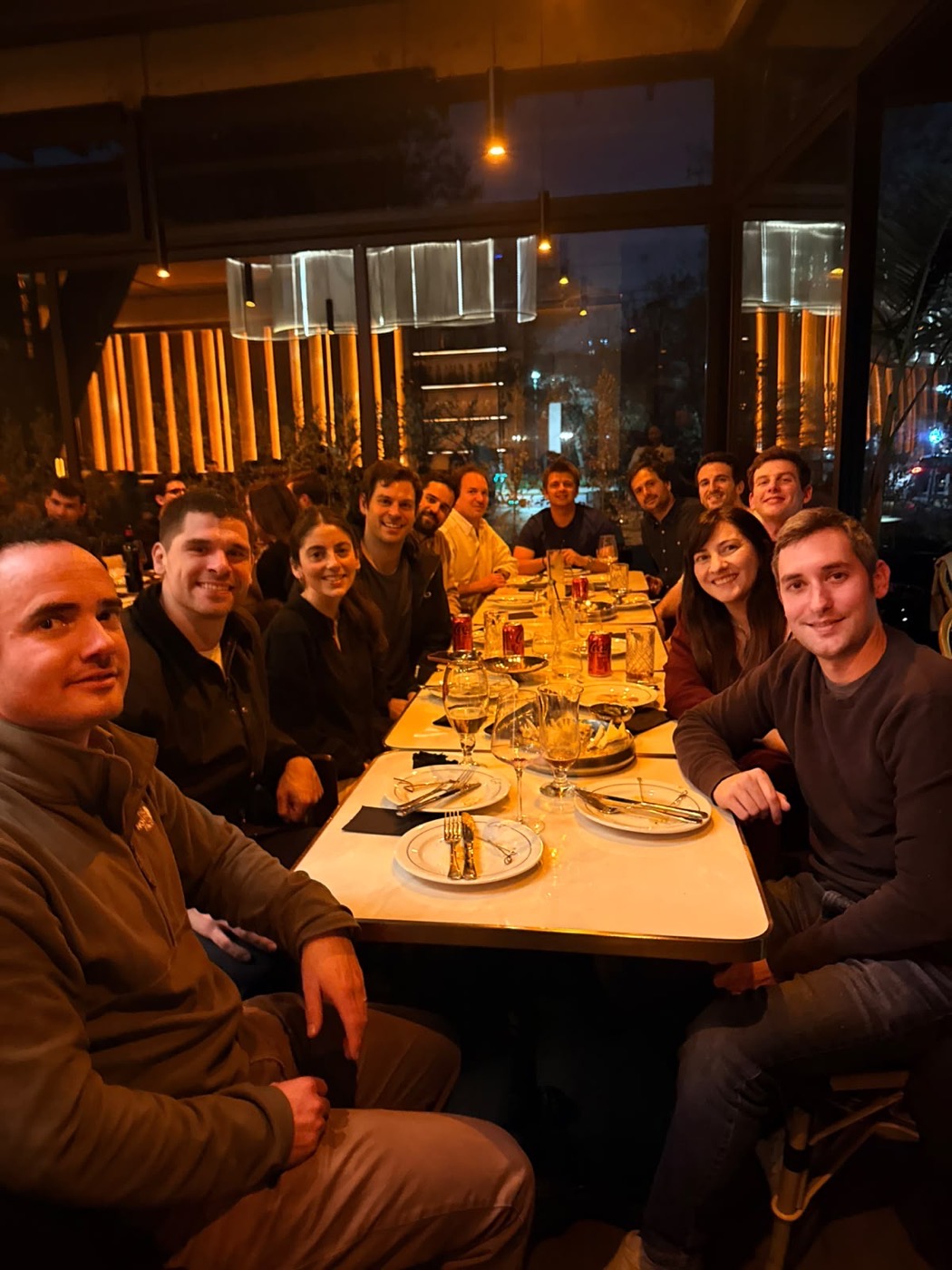 La mesa larga de la cena de despedida en CNIT: doce personas sentadas a ambos lados, mirando a la cámara.